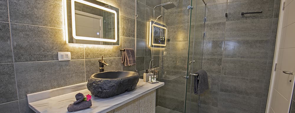 An image of a newly remodeled bathroom with stone tiling and glass shower