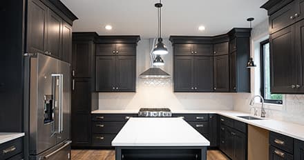 Newly renovated kitchen with dark cabinets to contrast white countertops and walls, with lots of natural light